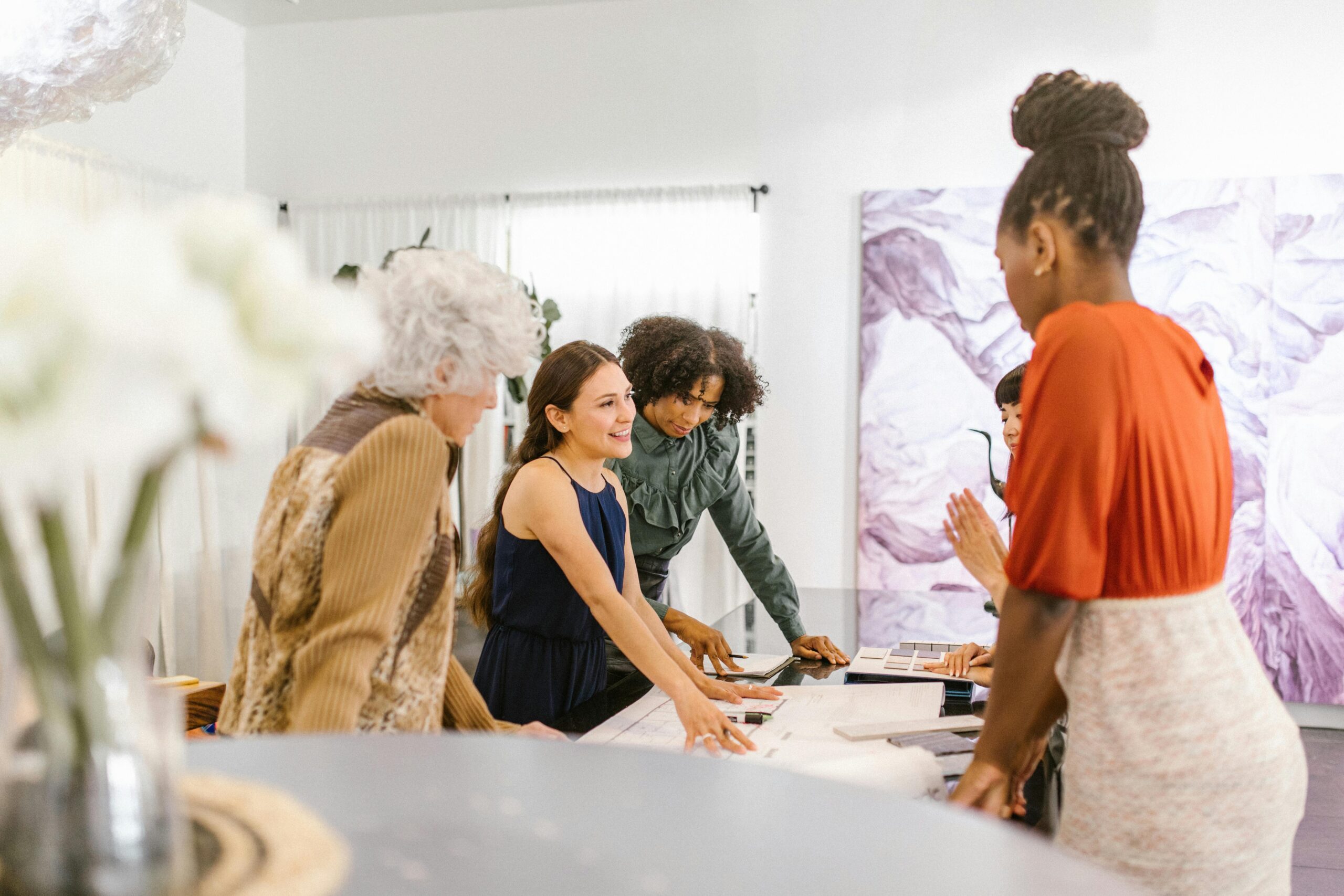 A diverse group of businesswomen discussing ideas together in a modern office setting.