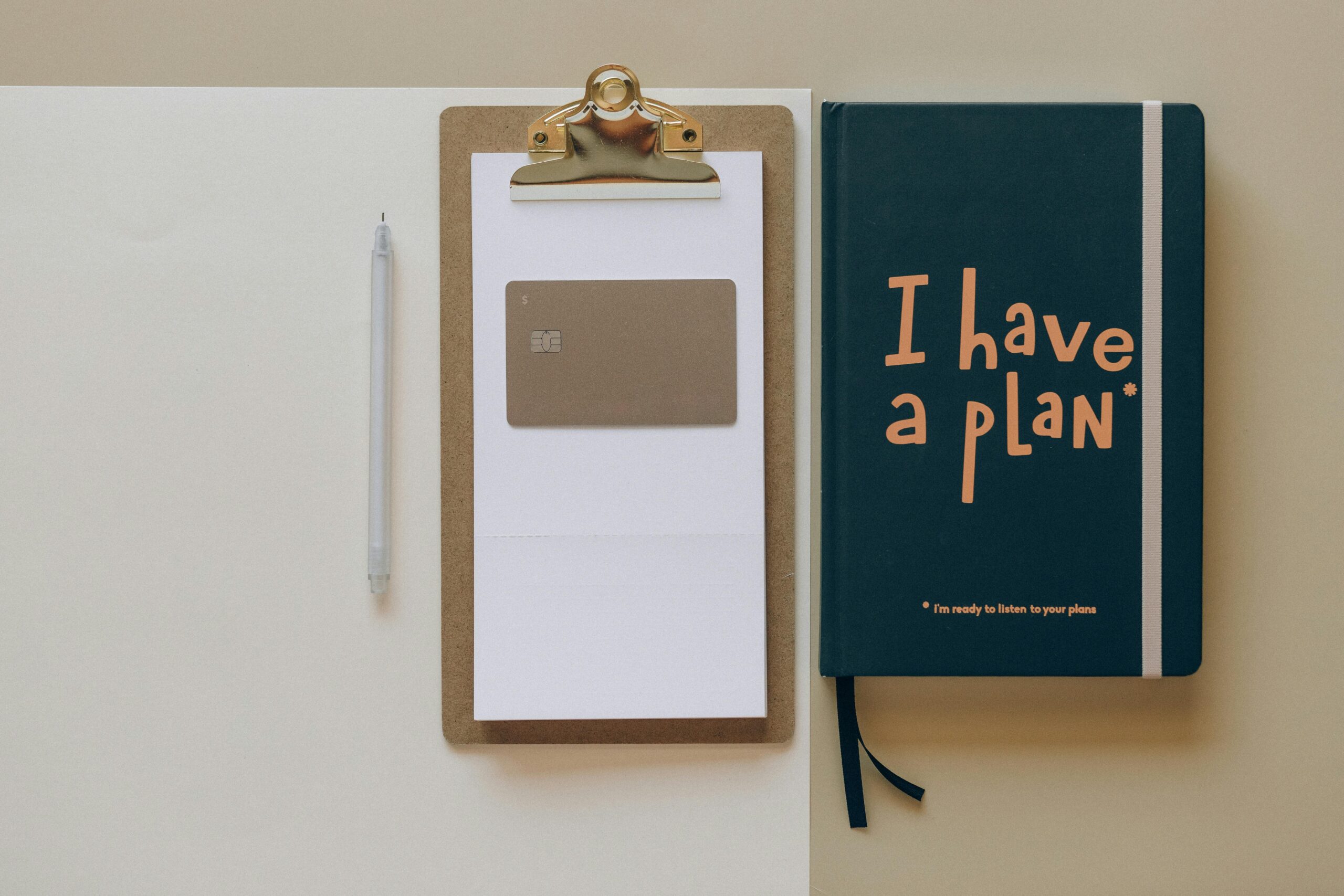 A minimalist office setup featuring a planner, clipboard, card, and pen, perfect for planning and organization.